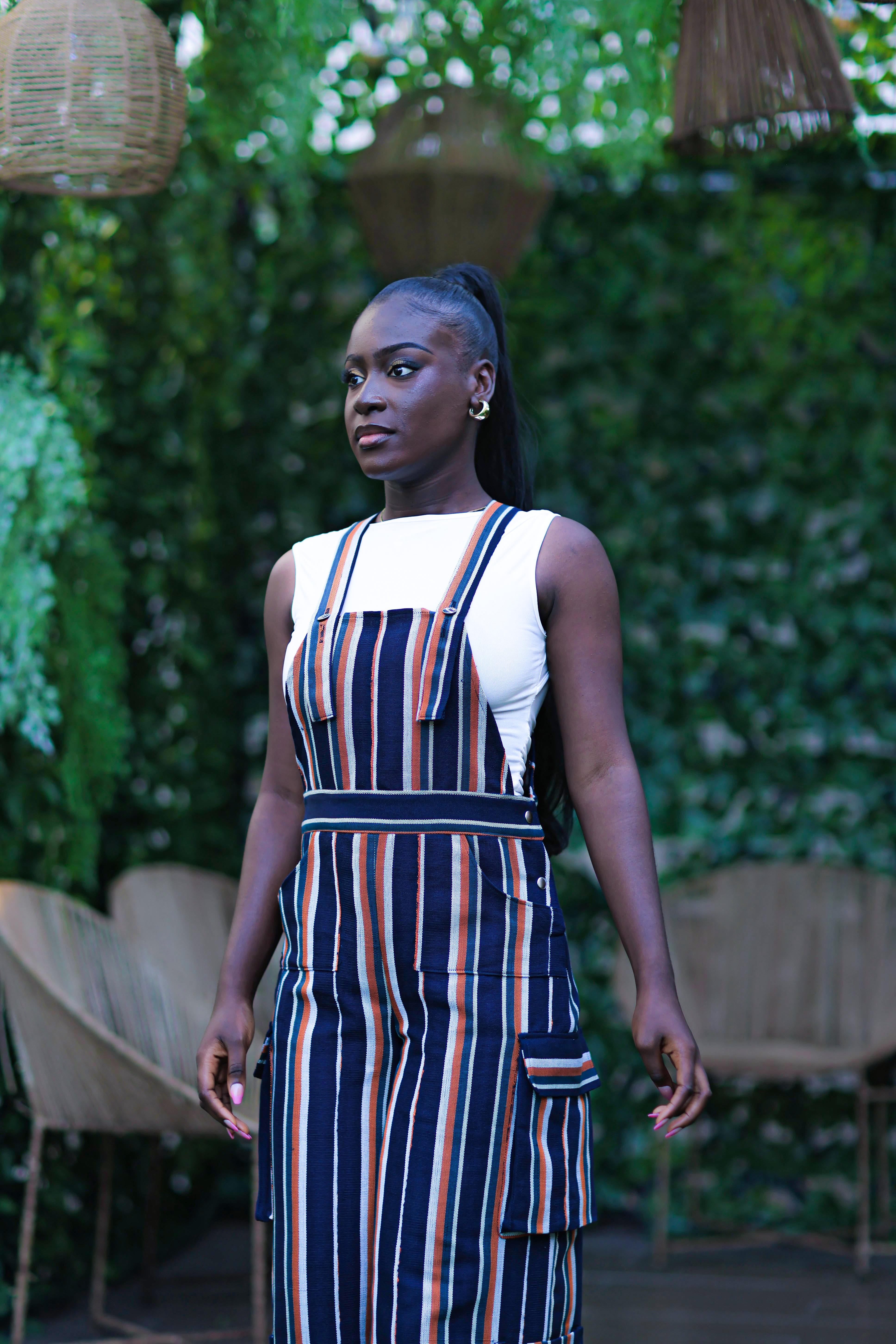 Woman wearing a striped dress standing outdoors with greenery in the background