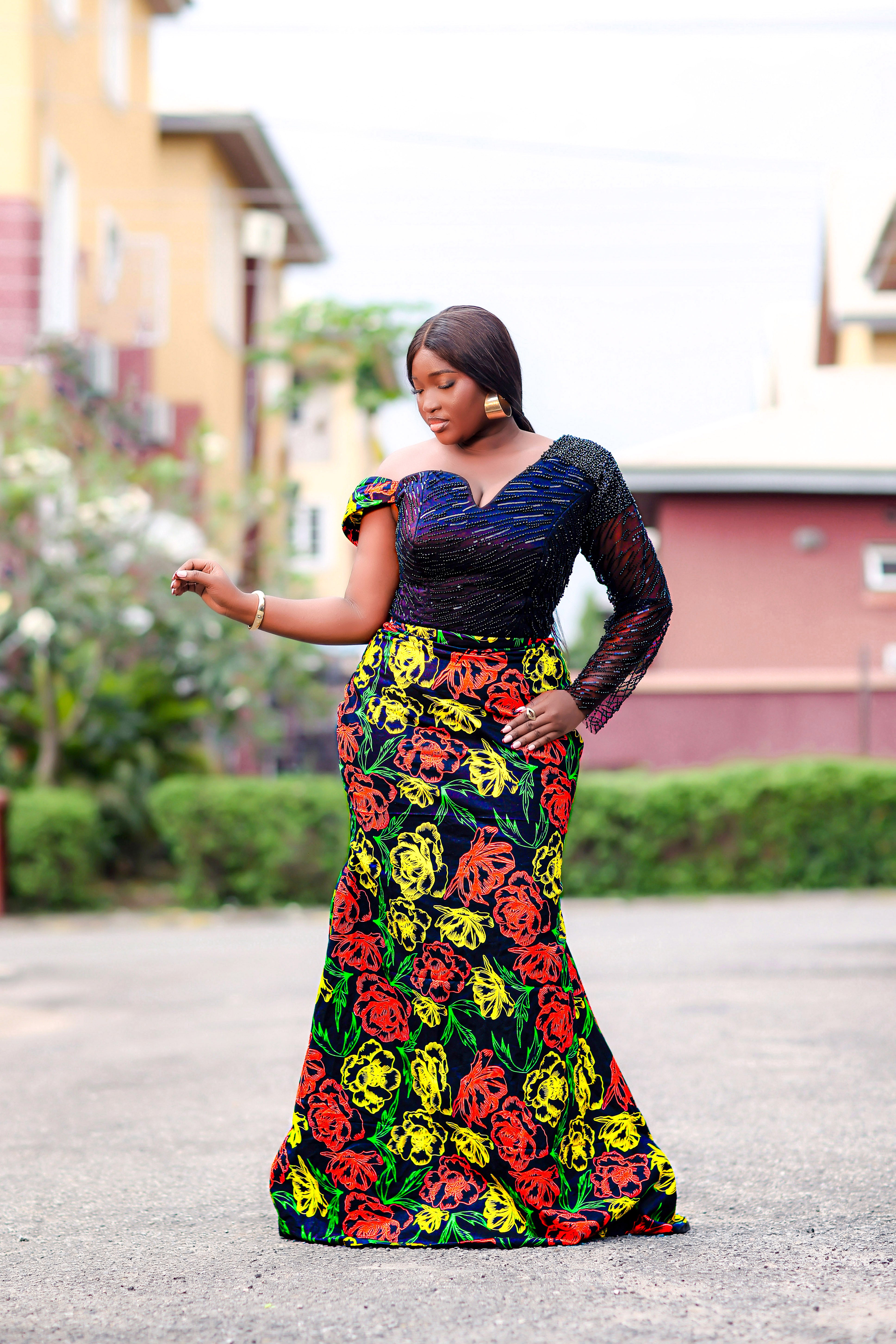 Women in a colorful floral African Print dress with embellished hand beaded upper bodice in black with headwraps standing in front of a decorated Christmas tree and fireplace.