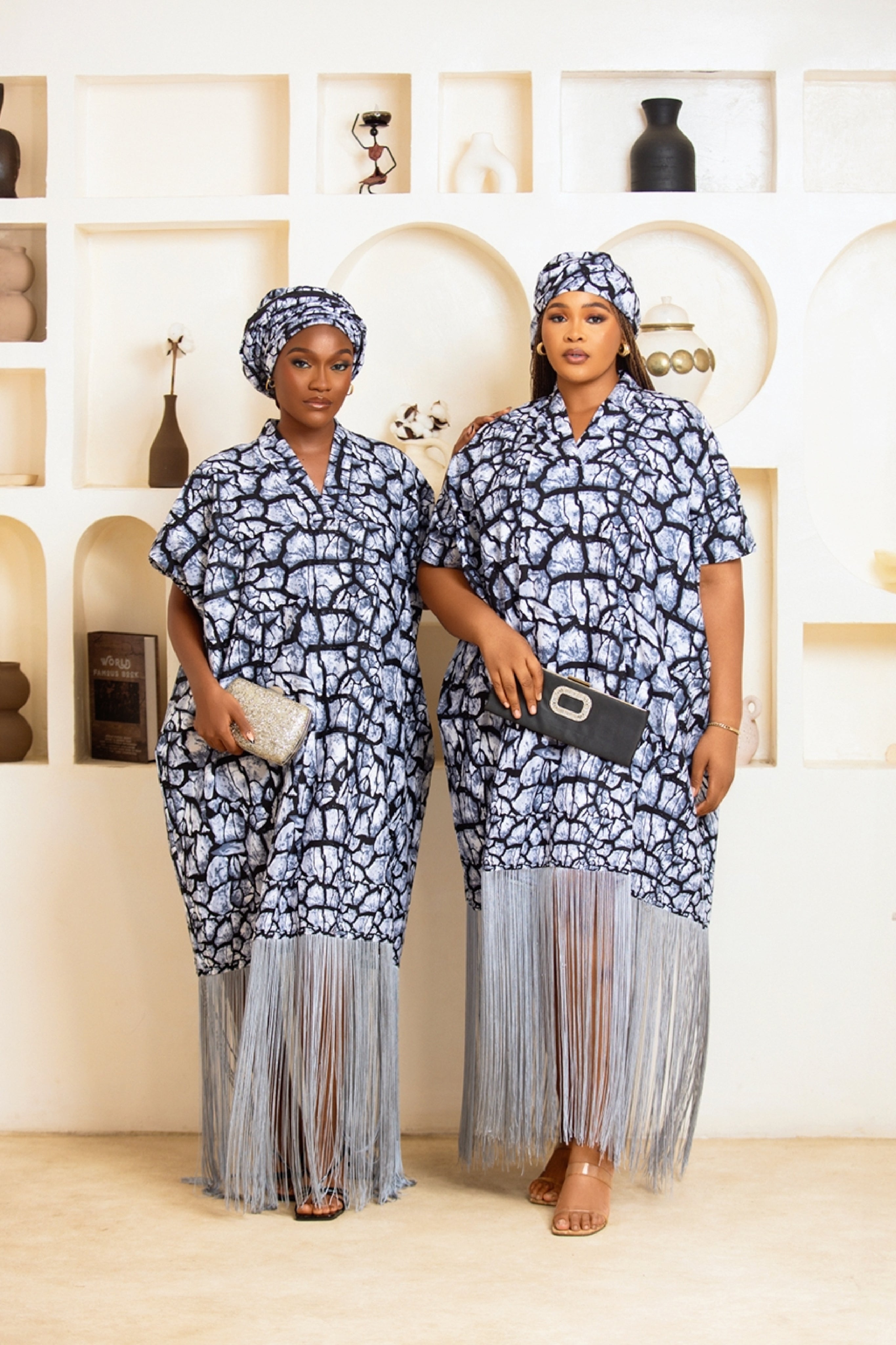 Woman in African Print Ankara Boubou dress outfit with headwrap, fringe and tassle details in grey silver black multicolor