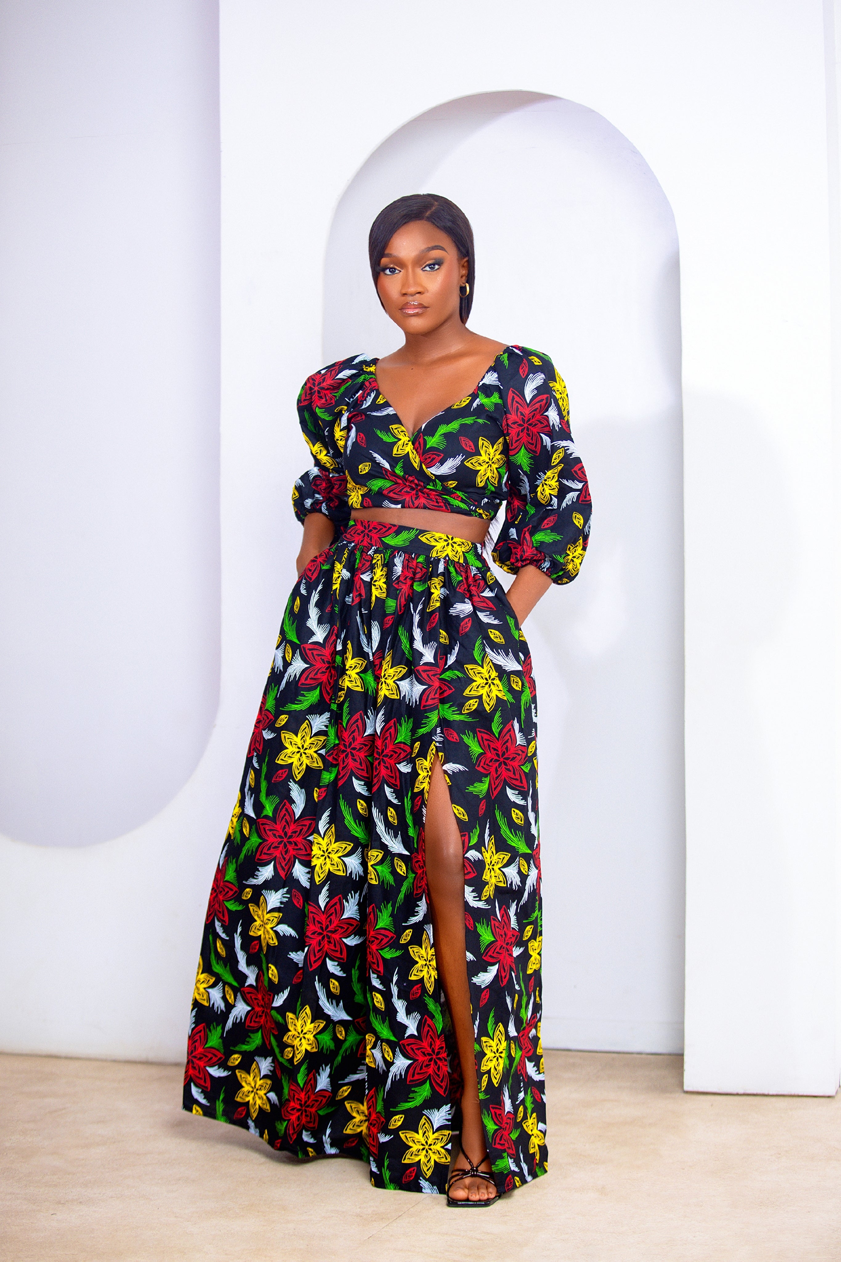 Woman wearing a colorful floral wrap top and maxi skirt dress set against a neutral background