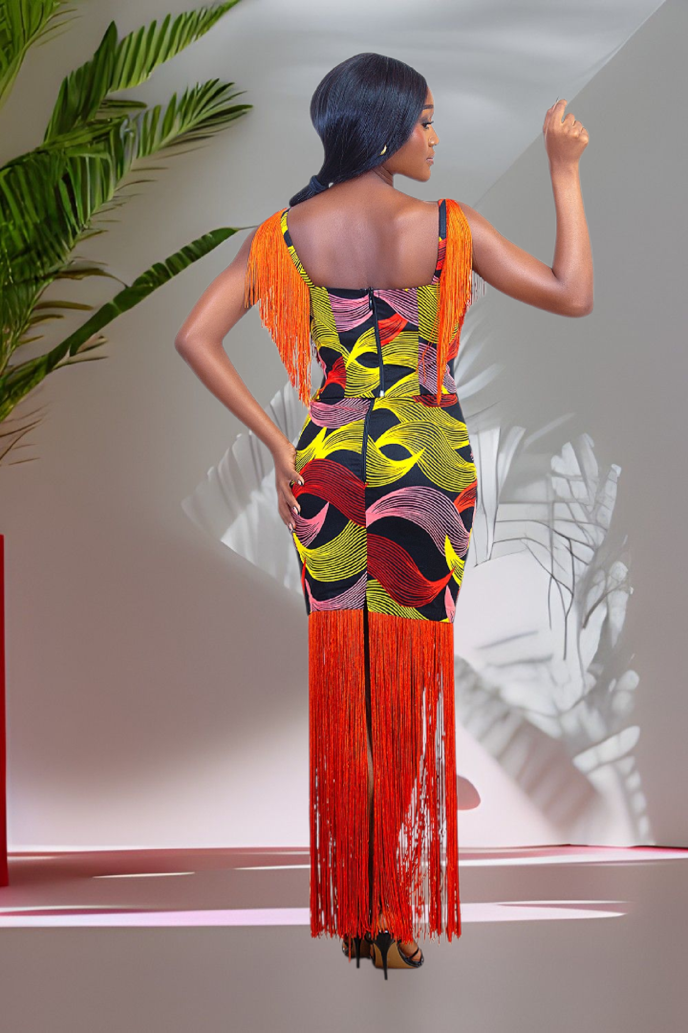 Woman wearing a colorful dress with orange fringes in a minimalistic setting