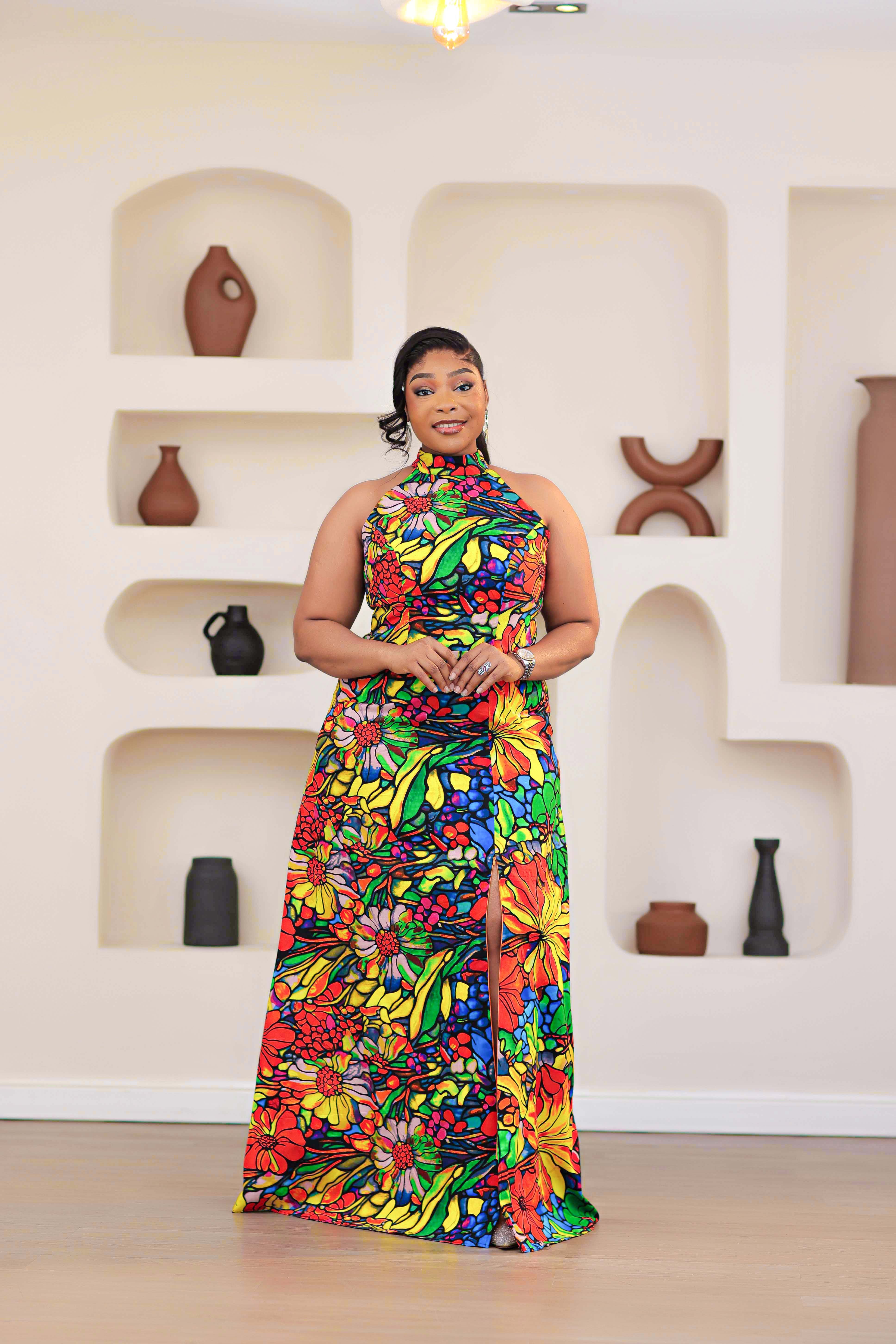 Woman wearing a colorful NIKI KAY African print ankara multicolor floral dress standing in front of a wall with decorative vases.