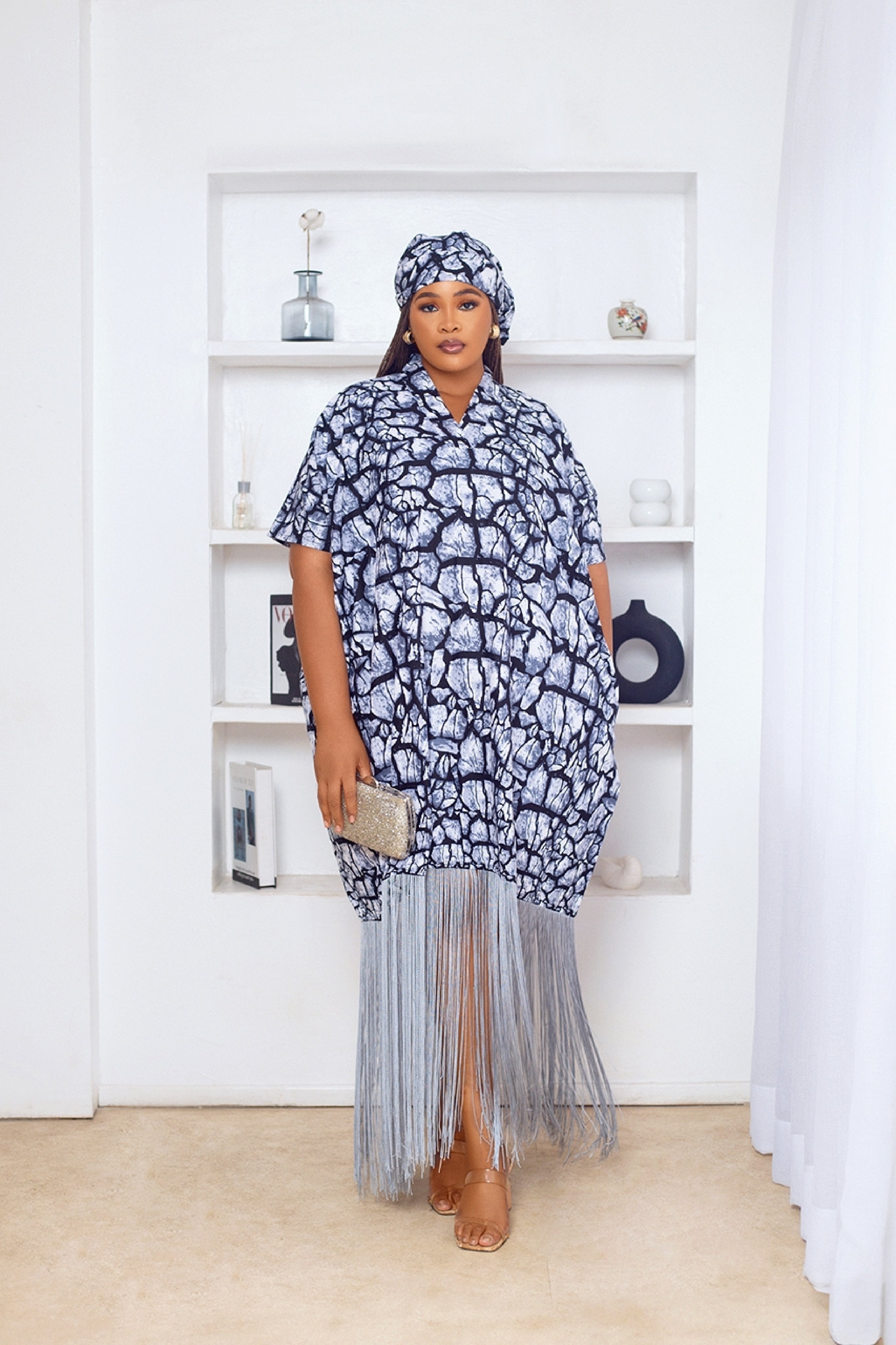 Woman in African Print Ankara Boubou dress outfit with headwrap, fringe and tassle details in grey silver black multicolor
