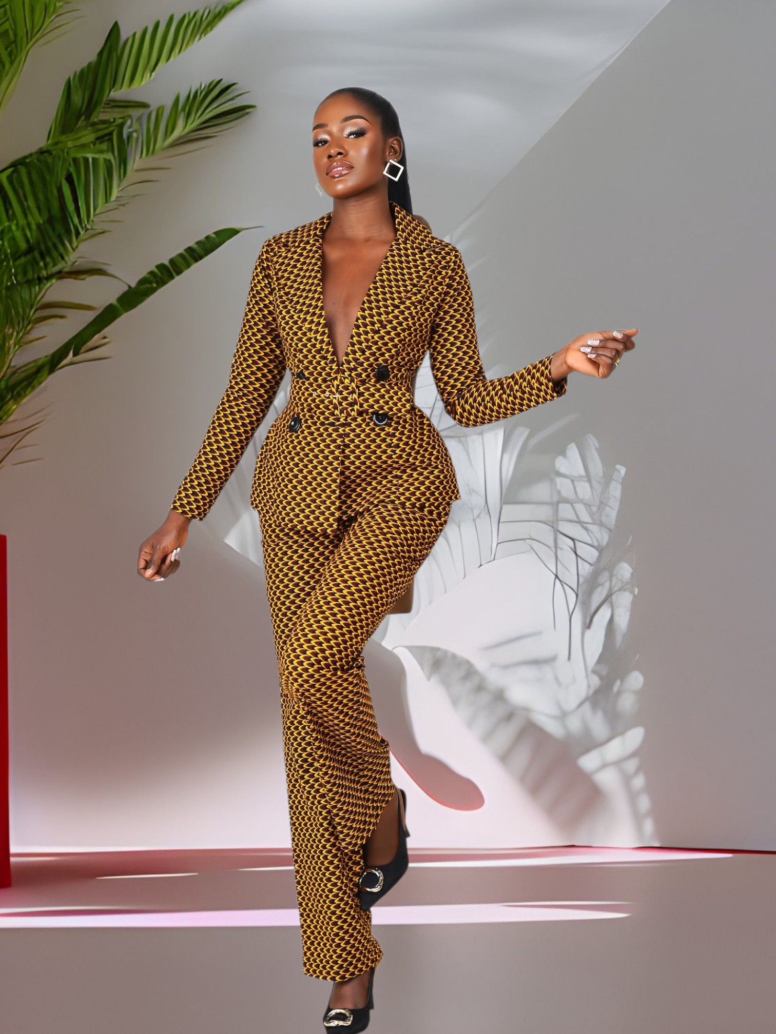 Woman in a patterned African Print Blazer and double breasted pantsuit set standing in a modern indoor setting with plants.
