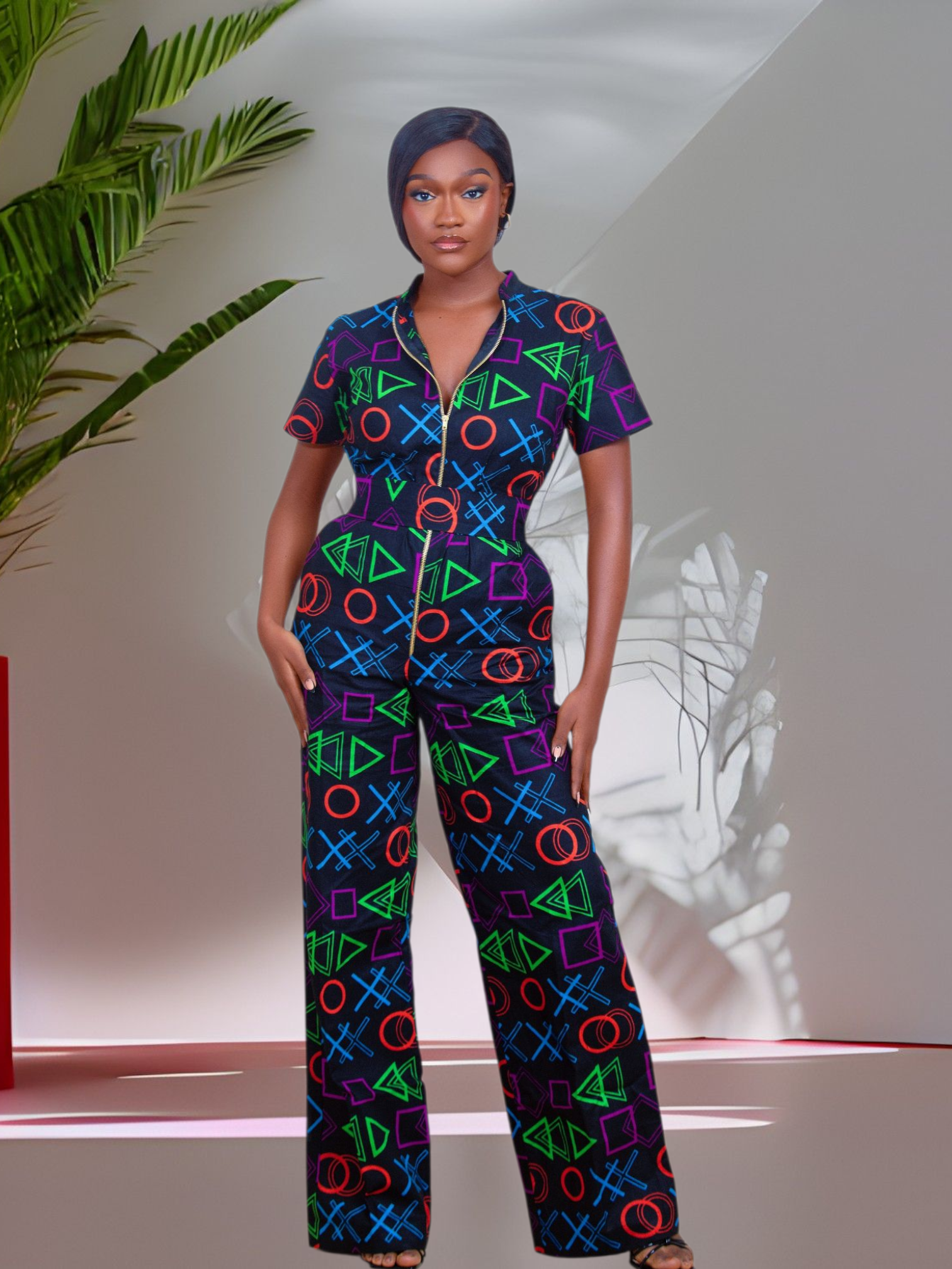Woman wearing a colorful geometric patterned jumpsuit outfit in a minimalistic setting with a plant.