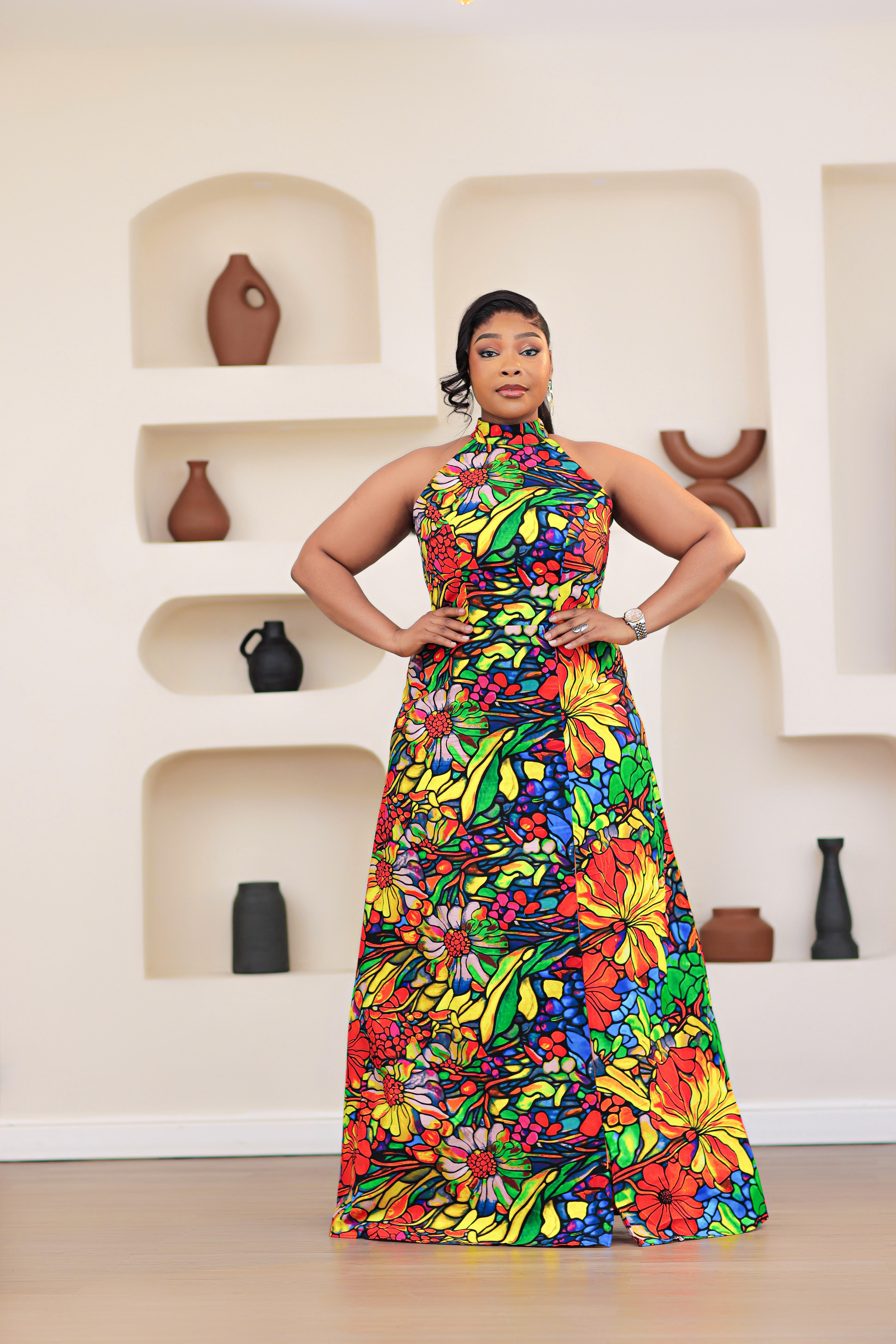 Woman wearing a colorful NIKI KAY African print Ankara multicolor floral dress standing in front of a wall with decorative vases.